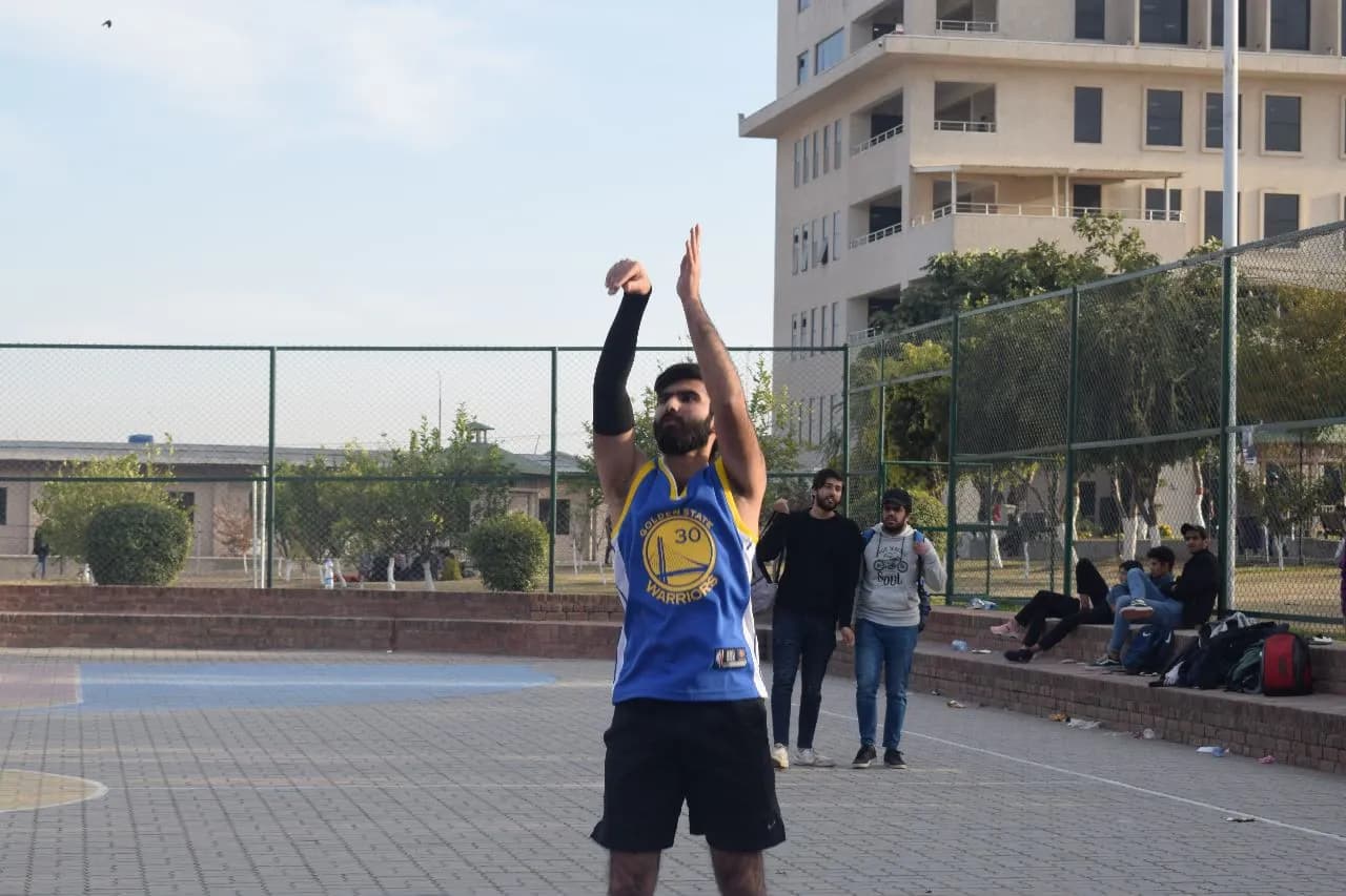 Abdullah taking a jump shot on an outdoor court.