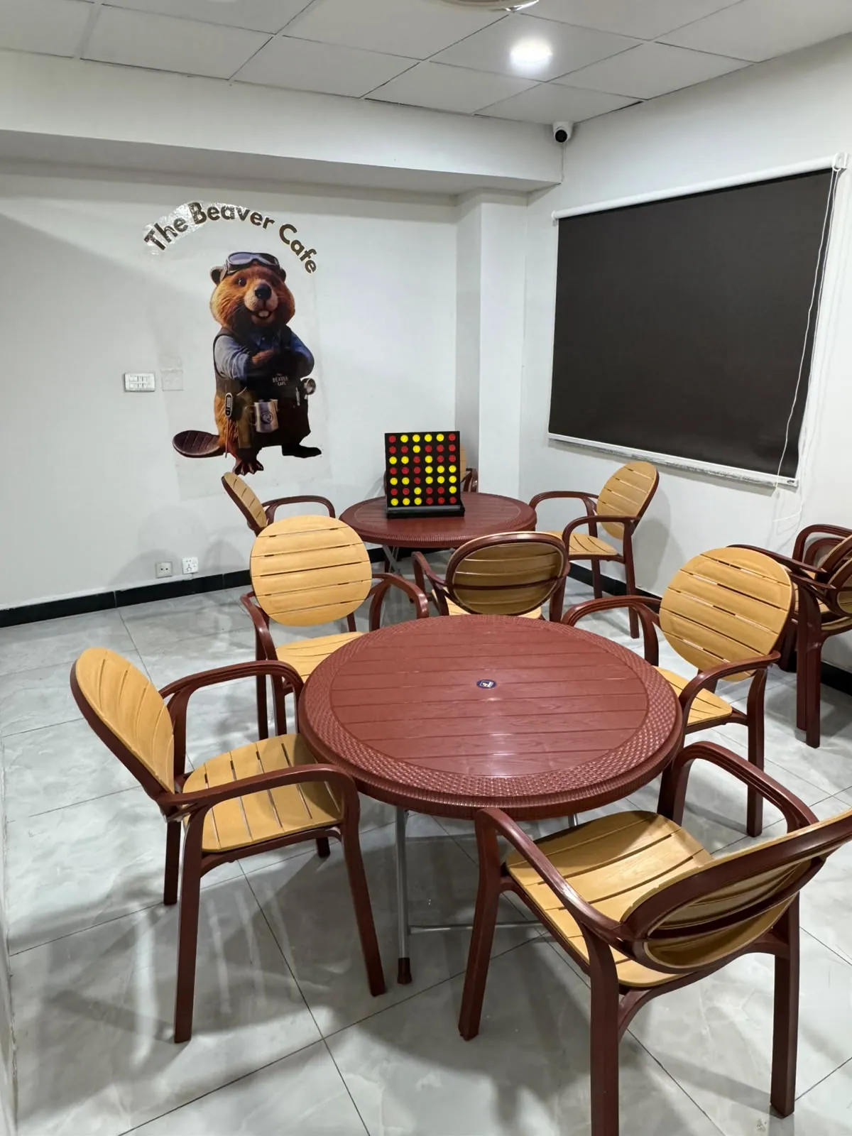 A corner with round tables and wooden chairs under a sign reading The Beaver Cafe.