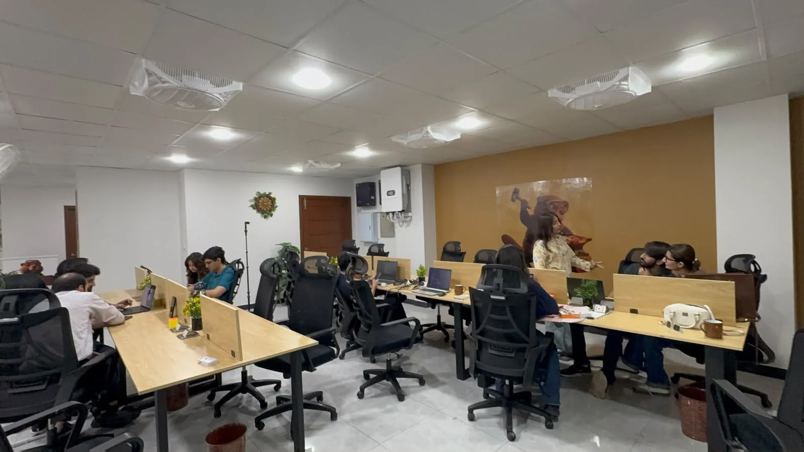 The main floor of The Forge with people working at long shared desks.